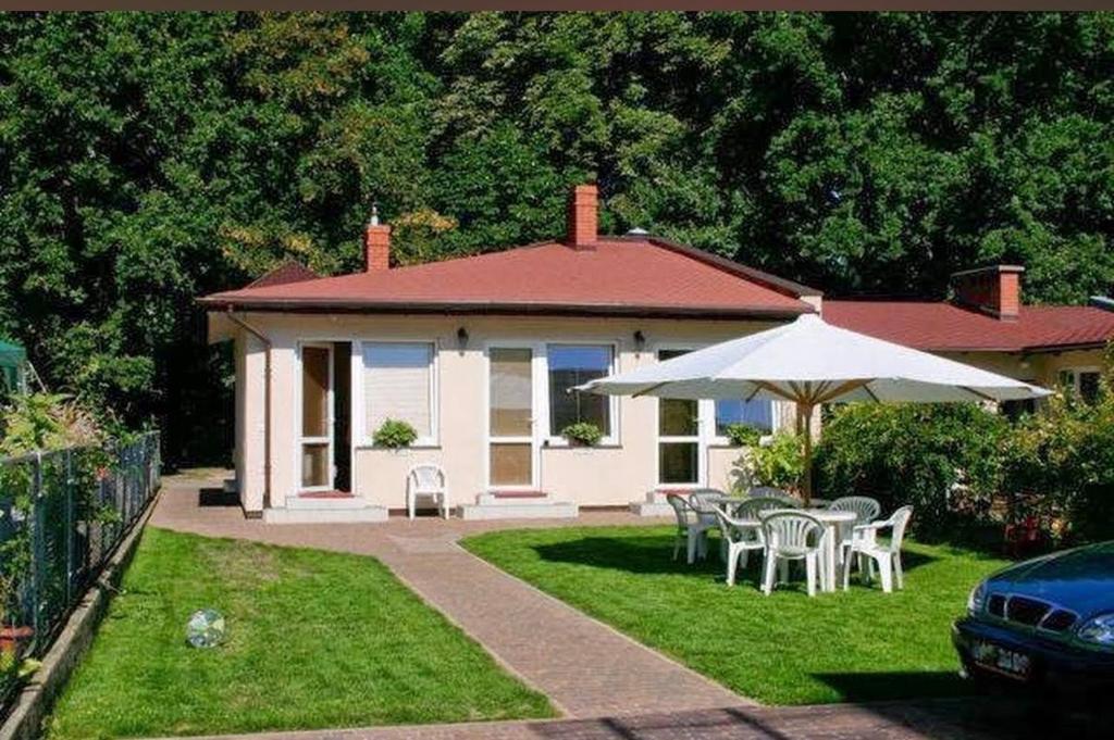 a house with a table and chairs and an umbrella at Baltic Garden Stay in Kołobrzeg
