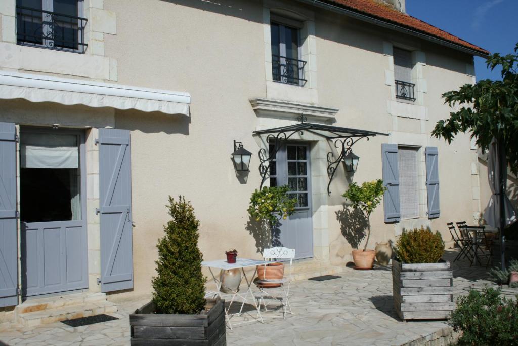 a white house with blue doors and a table and chairs at La maison de Charlotte - chambres d'hôtes-Futuroscope in Amberre