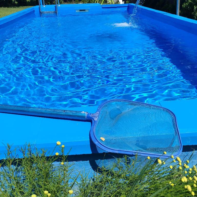 a blue swimming pool with a tub in the water at Mirella apartman in Palić