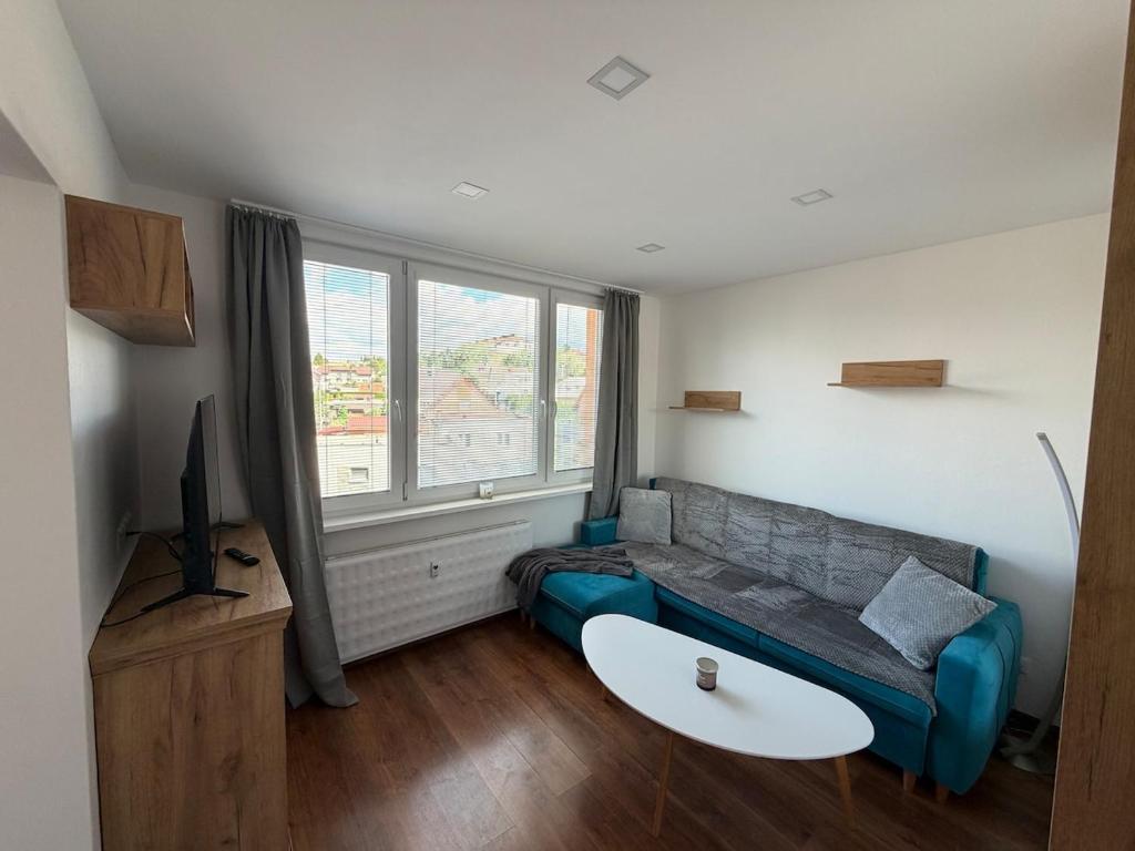 a living room with a blue couch and a tv at Modern stylish apartment in Prievidza