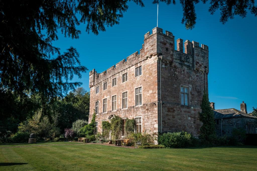a large brick building with a tower on a grass field at Askham Hall in Askham