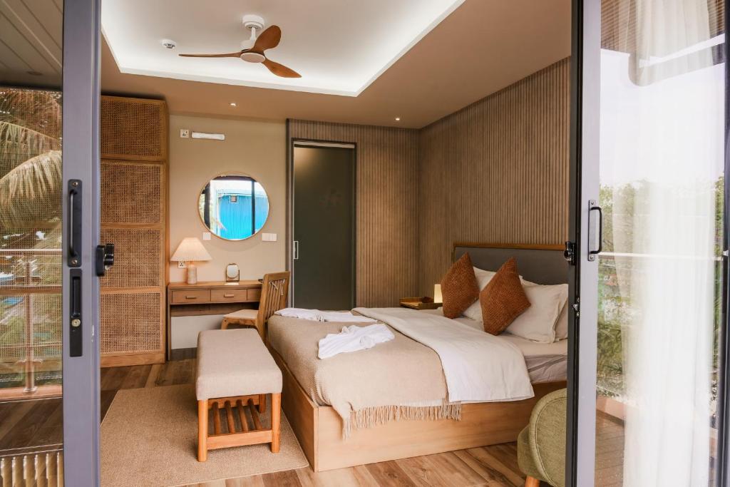 a bedroom with a bed and a desk and a mirror at Island Ufaa Dharavandhoo in Dharavandhoo