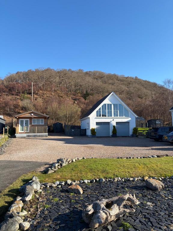 a white house with a hill in the background at Rockpool Apartment in Acharacle