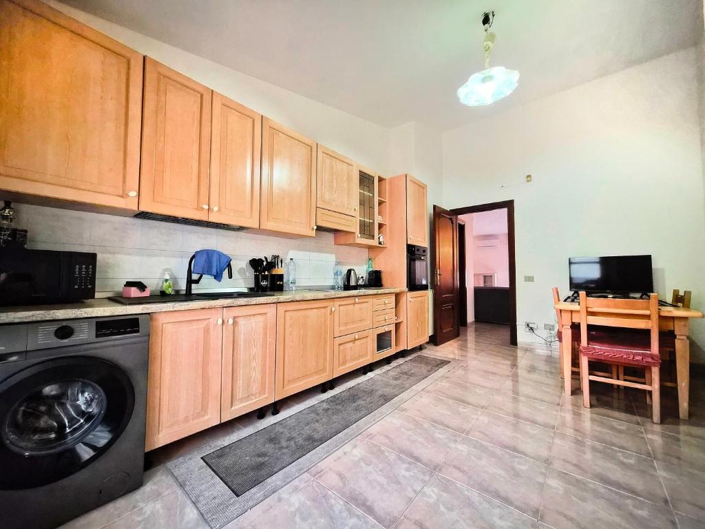 a kitchen with wooden cabinets and a washing machine at Big Apartment in Assemini