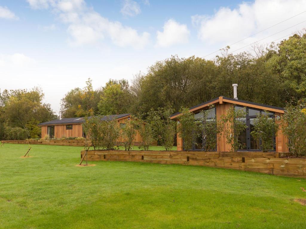 a wooden house in a field with a garden at Maple Lodge in Hassocks