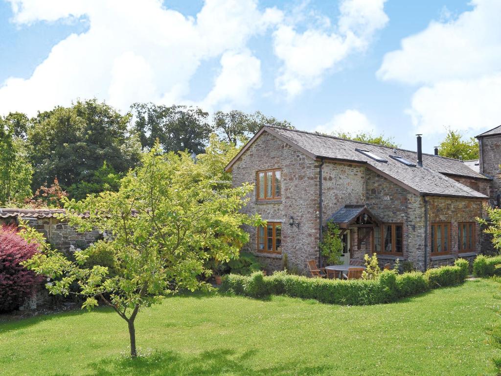 a stone house with a tree in a yard at The Appleloft in Westleigh