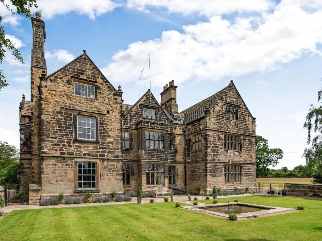 an old stone house with a grass yard at Hodroyd Hall in Holmfirth