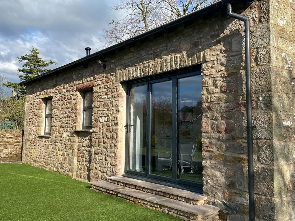 a stone house with a large glass window at Blue Heron Lodge in Brough
