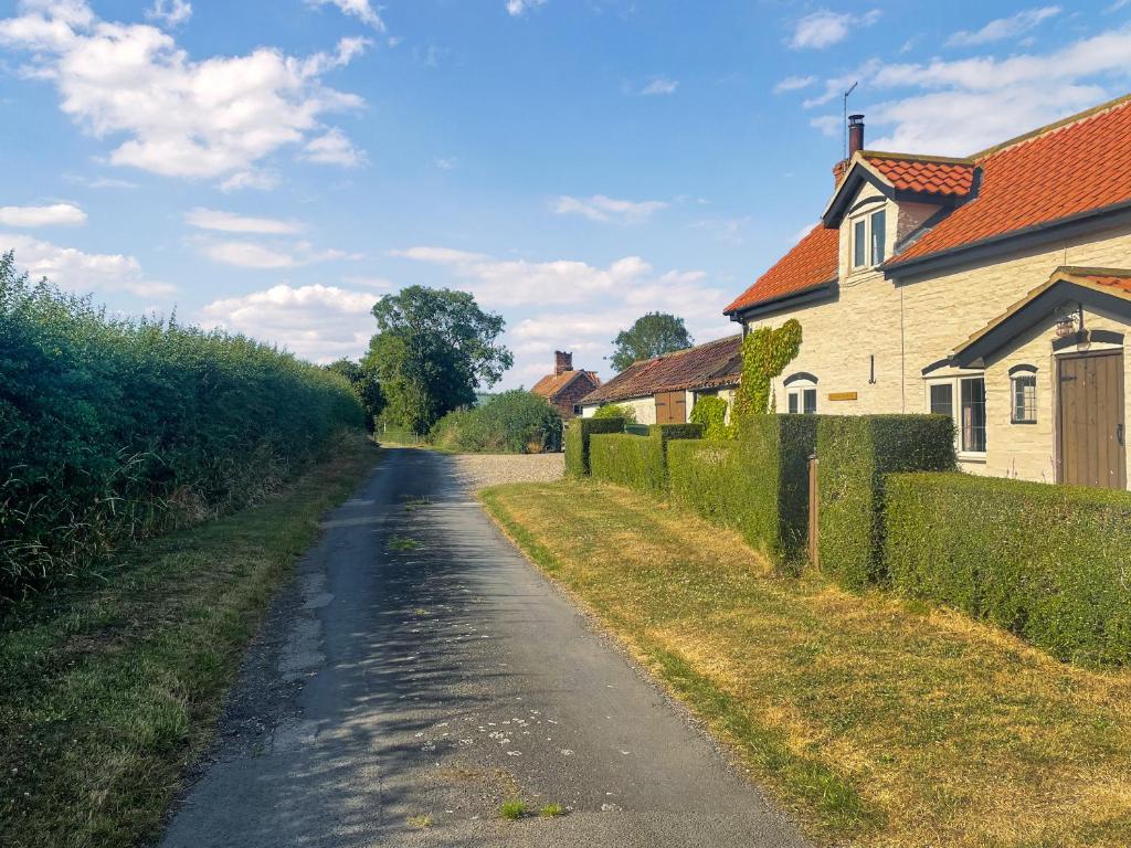 a dirt road next to a house and a fence at Winship Cottage in Winestead