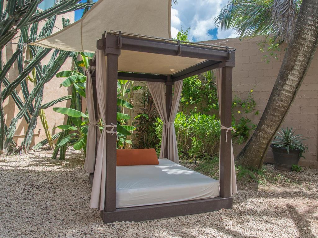 a bed in a canopy in a garden at Hotel Barrio Latino in Playa del Carmen