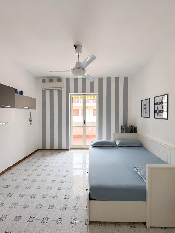 a bedroom with a blue bed and a kitchen at VitaDaMare in Giardini Naxos
