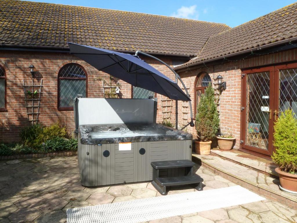 a barbecue grill with an umbrella in a backyard at Lambourne House - Ukc2831 in Skegness