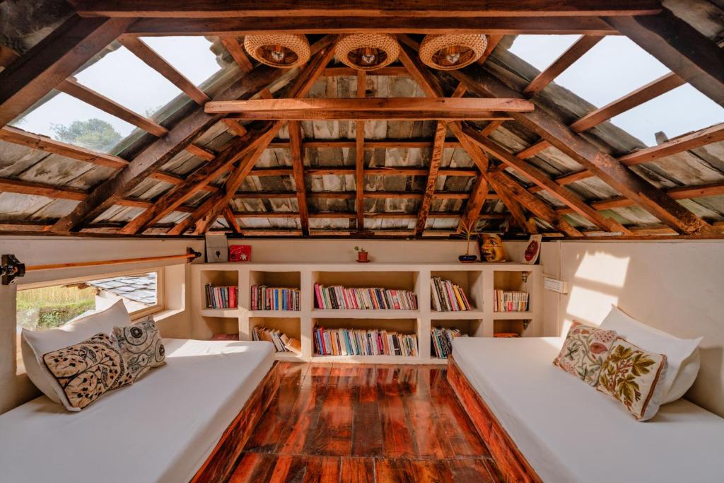 an attic room with two beds and bookshelves at The Attic Library by AVVAs Stays in Bīr