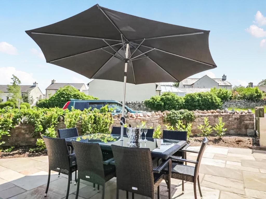 a table and chairs with an umbrella on a patio at Garth End in Appleby