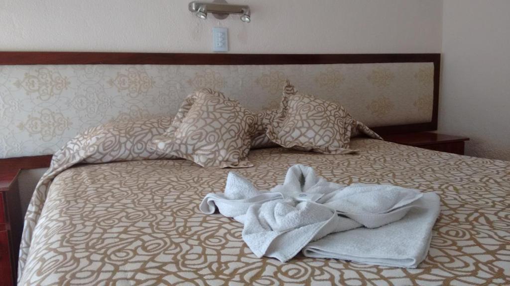 Una cama con toallas y almohadas. en Hotel Neptuno en Miramar