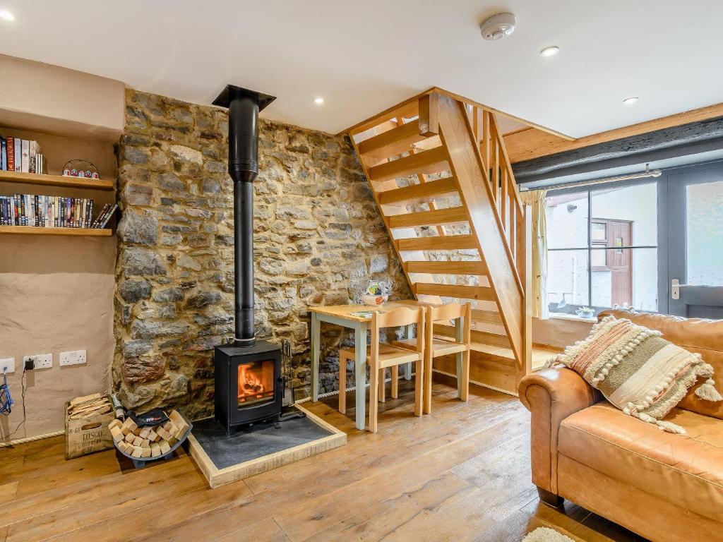 a living room with a stone wall and a wood stove at Stable Cottage in Pembroke