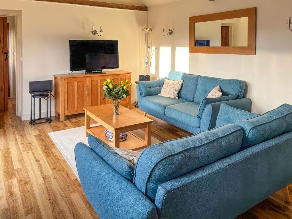 a living room with two blue couches and a television at The Stables in Occold