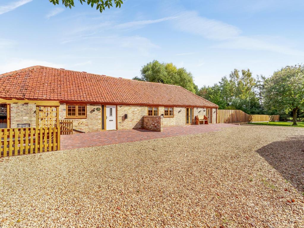 an old stone house with a gravel driveway at Woodpecker Barn - Uk38613 in Wisbech