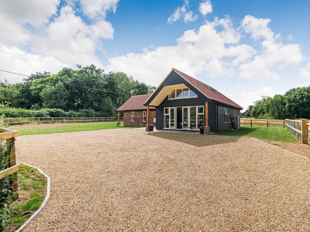 a barn with a gravel driveway in front of a house at Kings Lodge in Neatishead