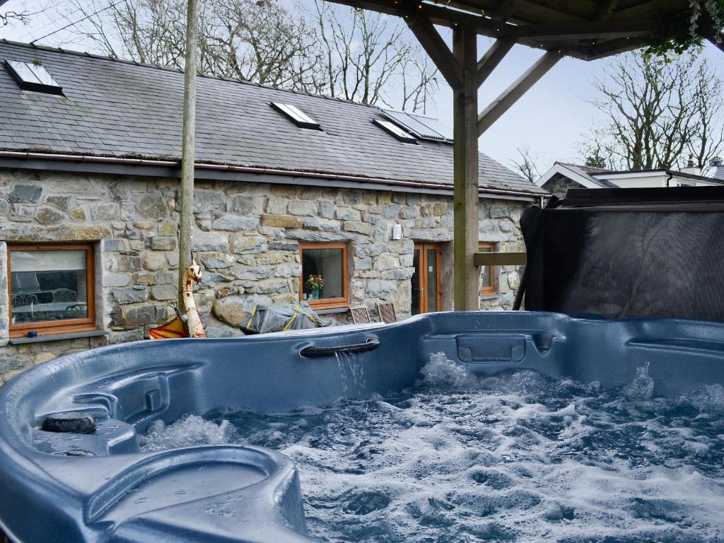 a blue hot tub in front of a stone house at Kris Kin in Criccieth