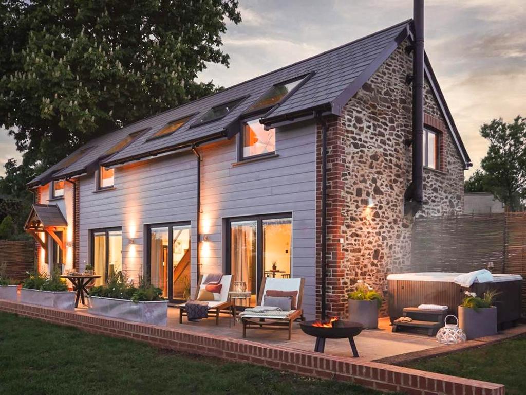 a house with a patio with two chairs and a table at Acacia in West Worlington