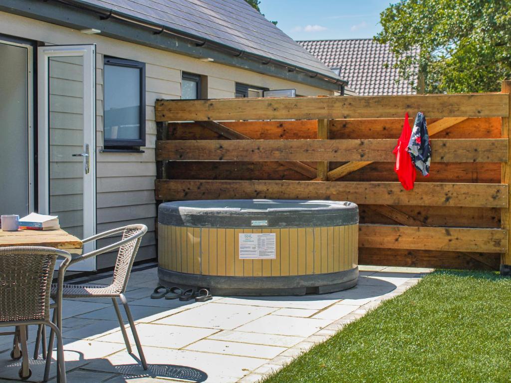 a wooden fence with a hot tub next to a table and chairs at No 8 Mouse Hole-Uk44302 in Sparham