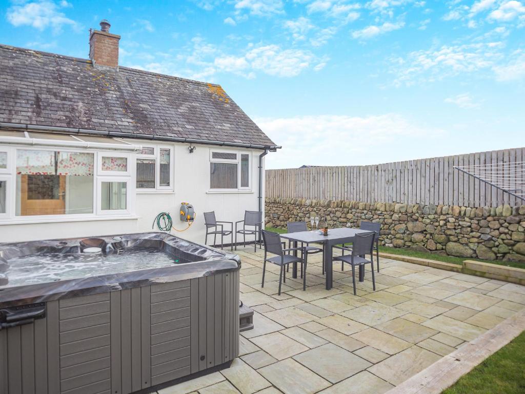 a patio with a table and chairs and a house at Swyn Y Don in Llanfair