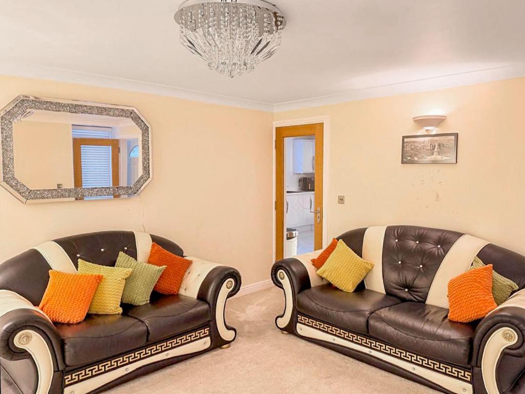 a living room with two leather couches and a mirror at Royal Border Retreat in Berwick-Upon-Tweed