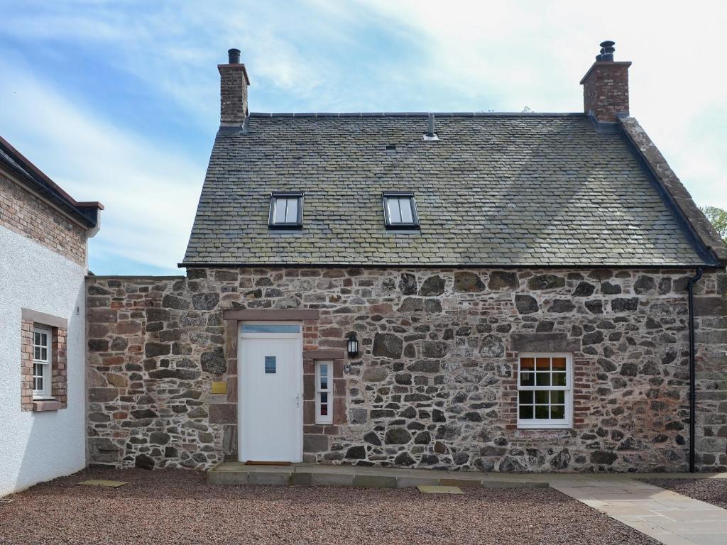 an old stone house with a white door and windows at Grieve's Cottage - Uk11107 in Montrose
