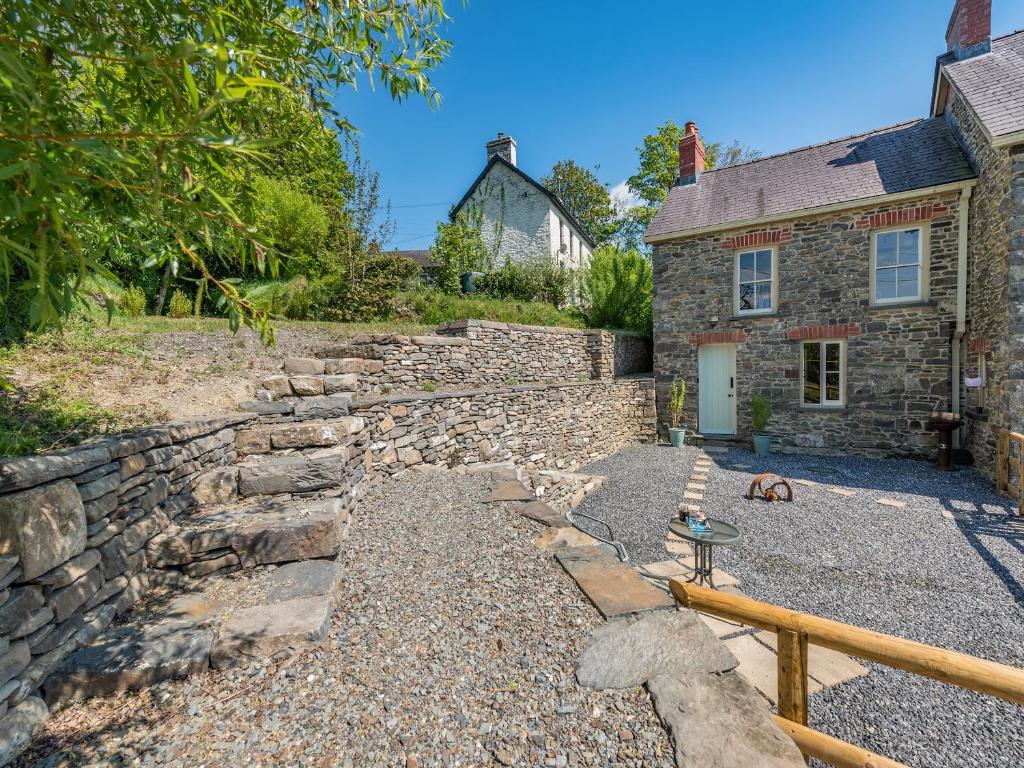 a stone retaining wall next to a house at Dyffryn Glanffrwd Mill in Cellan