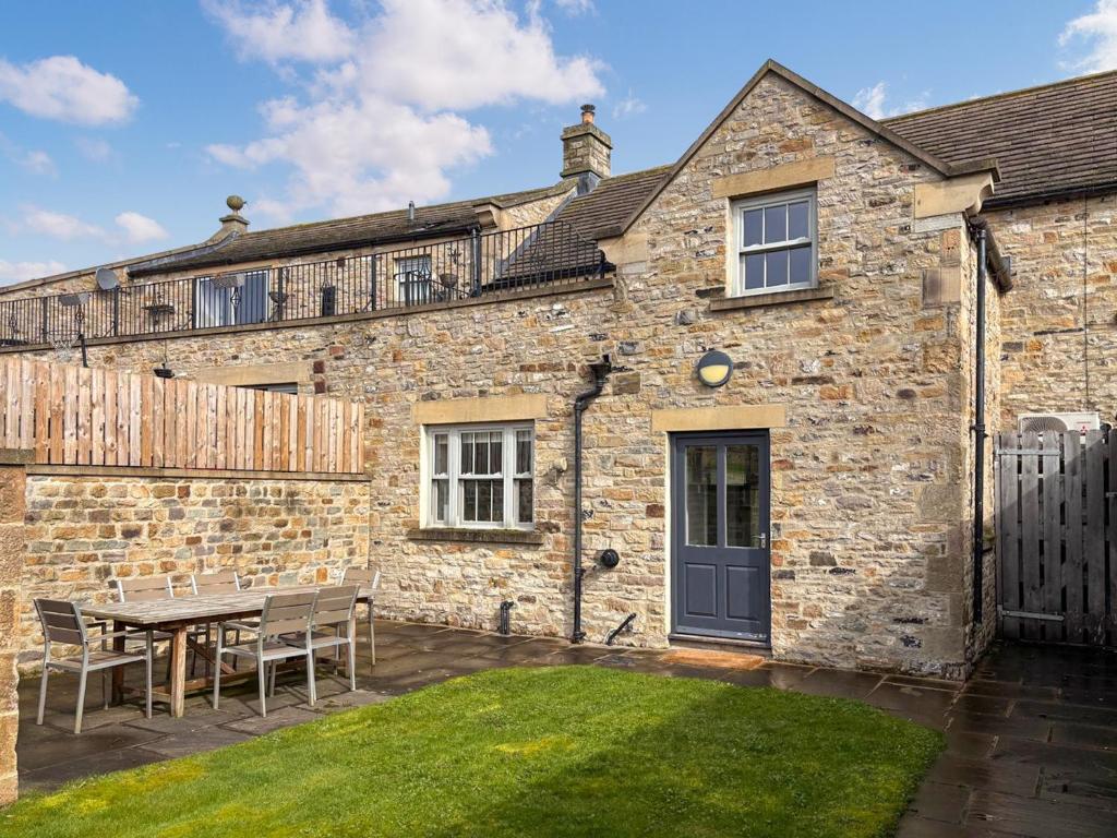 a brick house with a table and chairs in the yard at Stable Cottage - Uk51669 in Leyburn