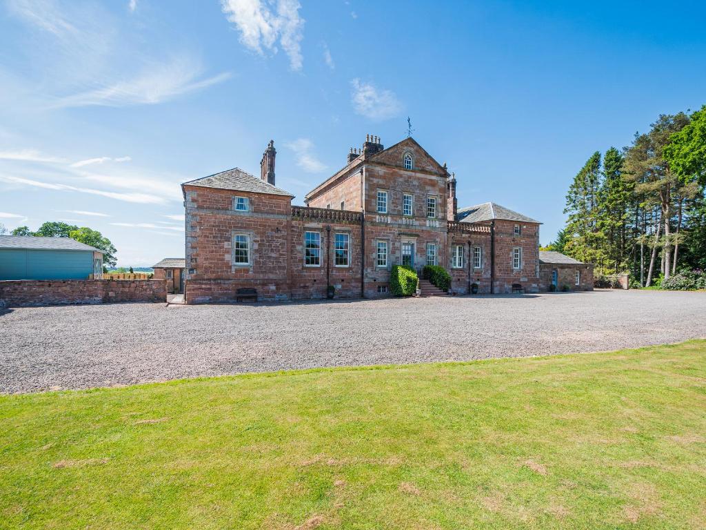 an old brick building with a grass field in front at Mossknowe Escape in Annan
