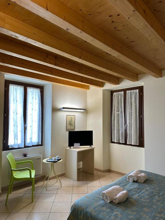 a bedroom with a bed and a desk and windows at Locanda Graziella in Moerna