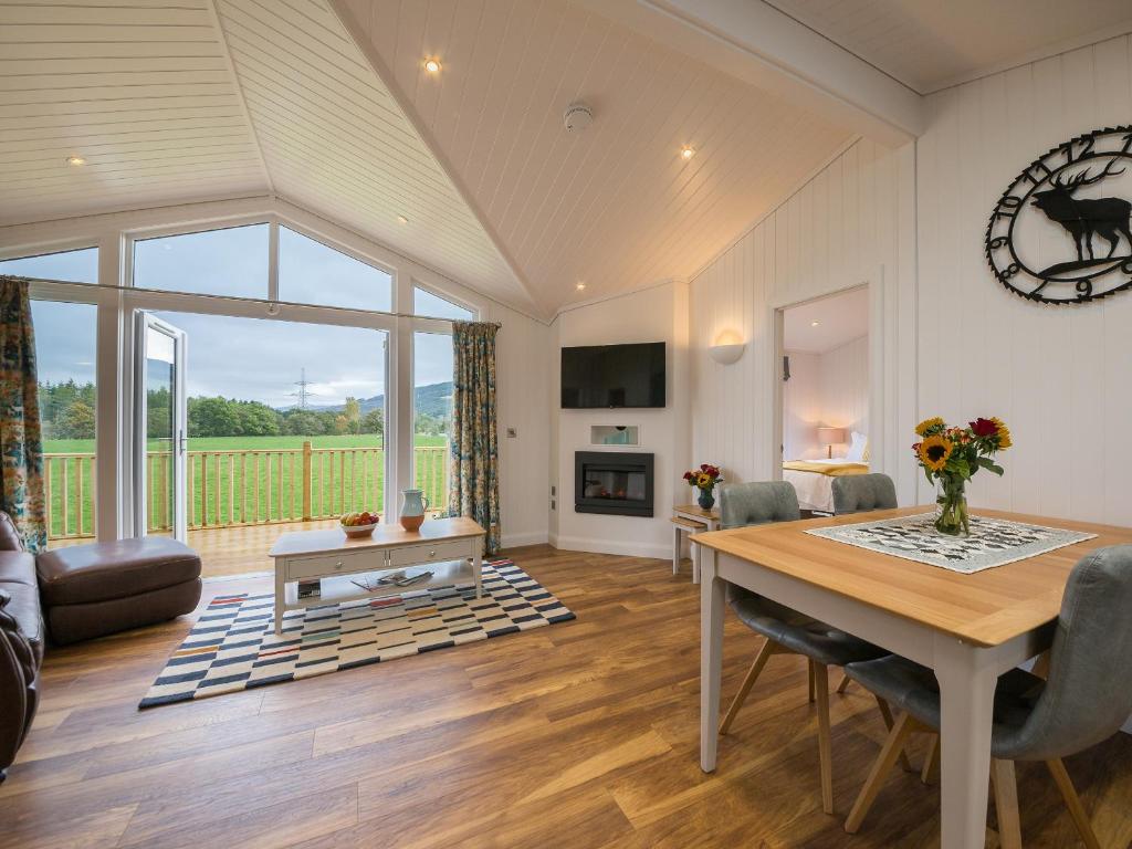 a dining room with a table and a living room with a view at Karelia Lodge in Kenmore