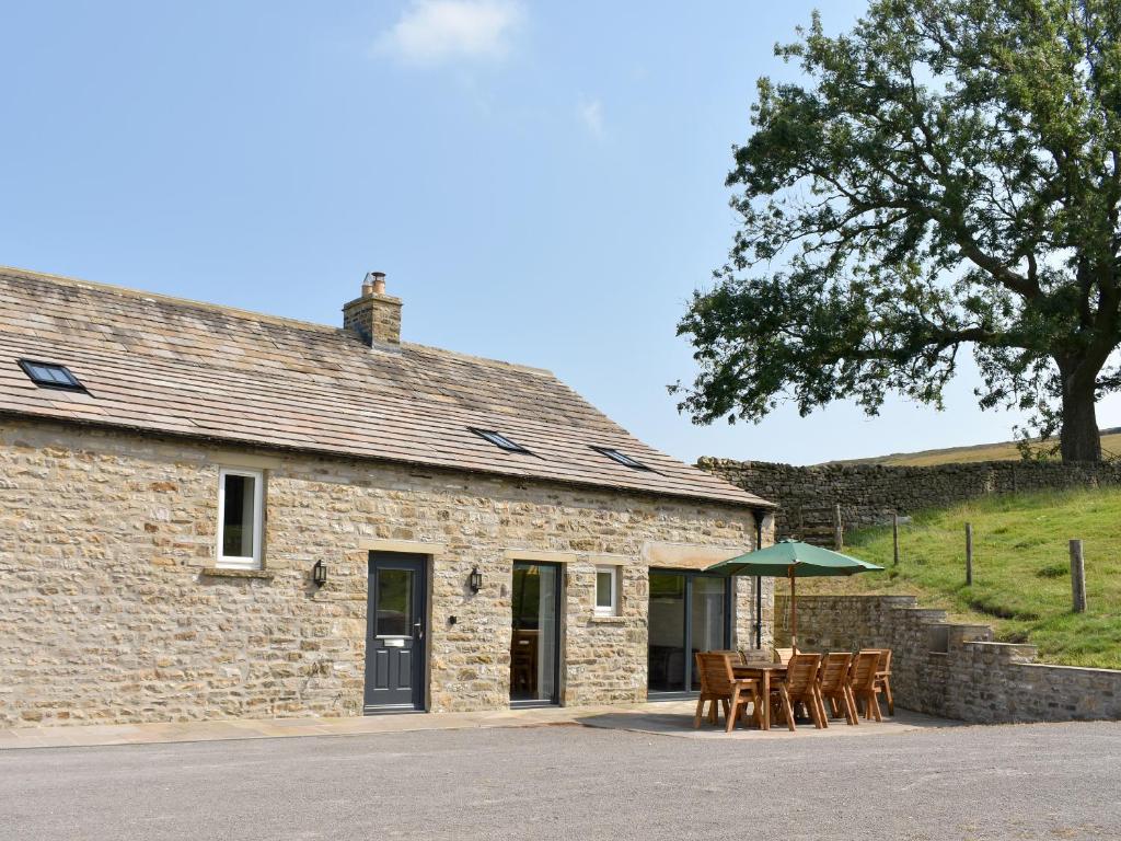 a stone house with tables and a green umbrella at Deer Park - Uk33360 in Reeth
