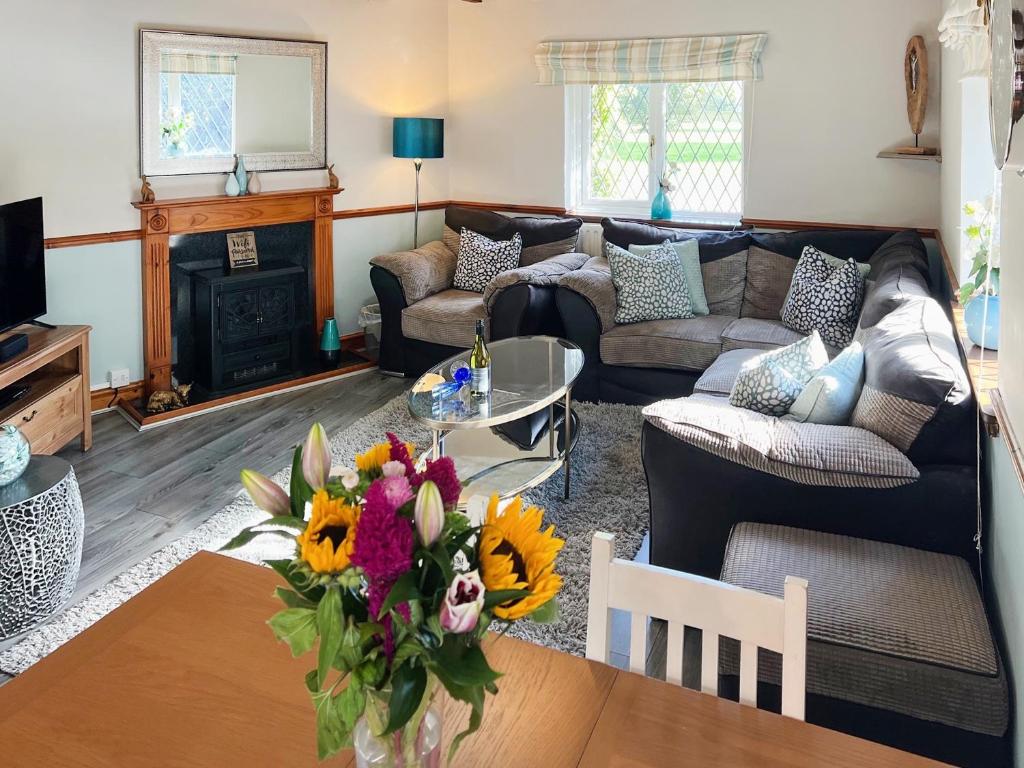 a living room with a couch and a table with flowers at Archways-E1223 in Addlethorpe