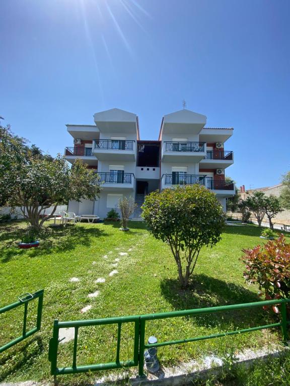 a large apartment building with a green fence in front of it at Nelli rooms in Polychrono