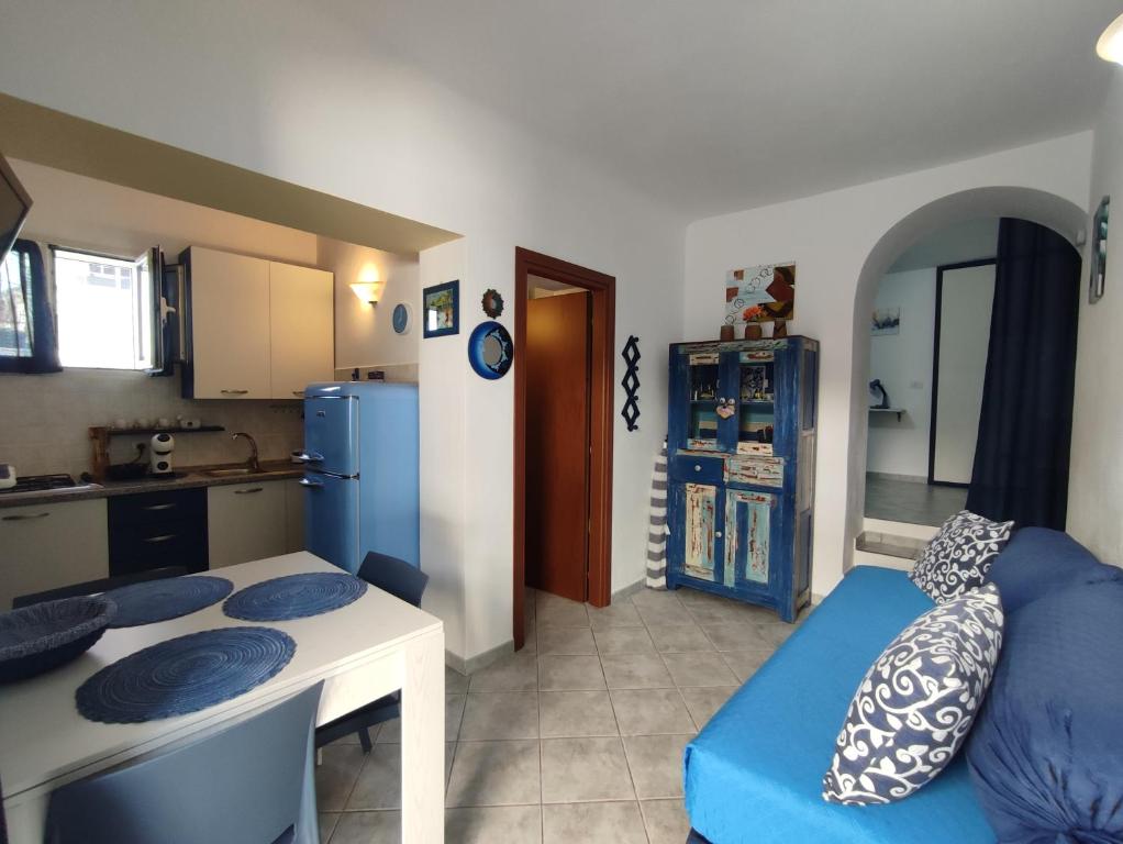 a kitchen and a living room with a blue couch at Appartamenti Conchiglie e Stelle Marine in Cala Gonone