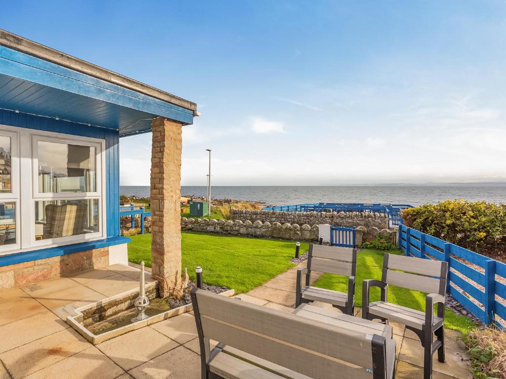 a house with two benches and a view of the ocean at Roggle Roich in Hilton of Cadboll