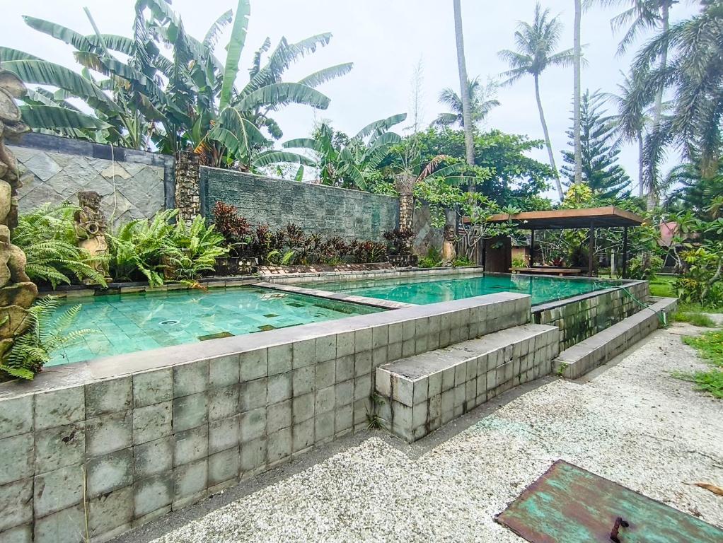 a swimming pool in a backyard with a stone wall at The Lavana Green Asri Cottage in Senggigi
