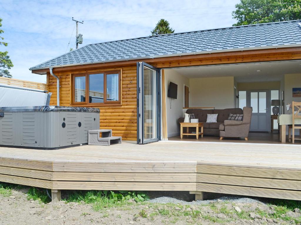 a log cabin with a deck and a heater at Sweet Meadow Lodge in Llandrindod Wells