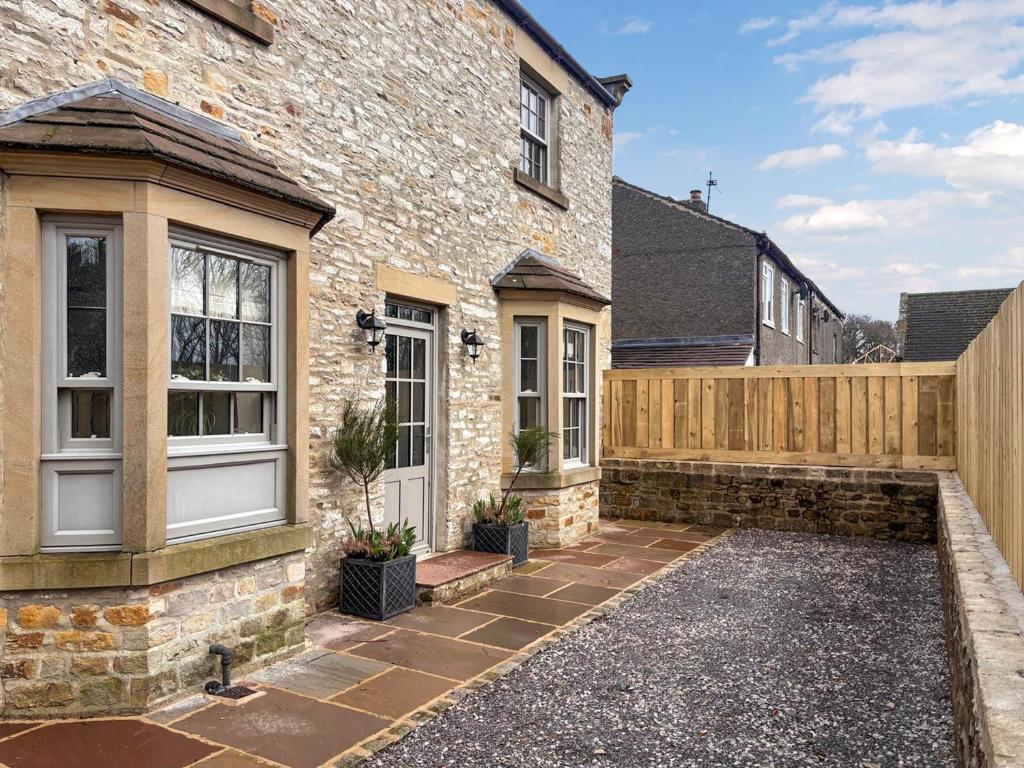 a brick house with a wooden fence on it at Ghyll Cottage - Uk51667 in Leyburn