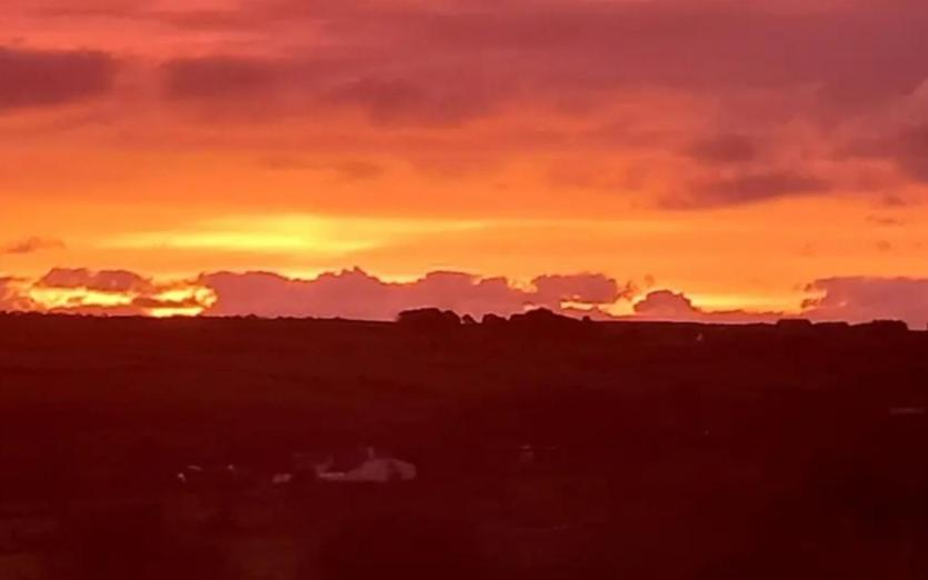 a sunset in a field with the sun setting at The Paddock at Pioneer Billys in Camborne