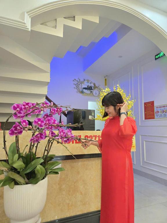 a woman in a red dress talking on a cell phone at Nhà Nghỉ Thuận Phát in Làng Chang