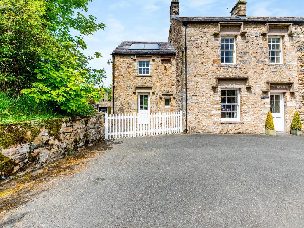 an old stone house with a white gate and a fence at Warth House - Uk44209 in Ingleton