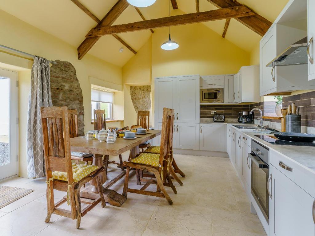 a kitchen with a wooden table and chairs at The Stables - Uk32514 in Marloes