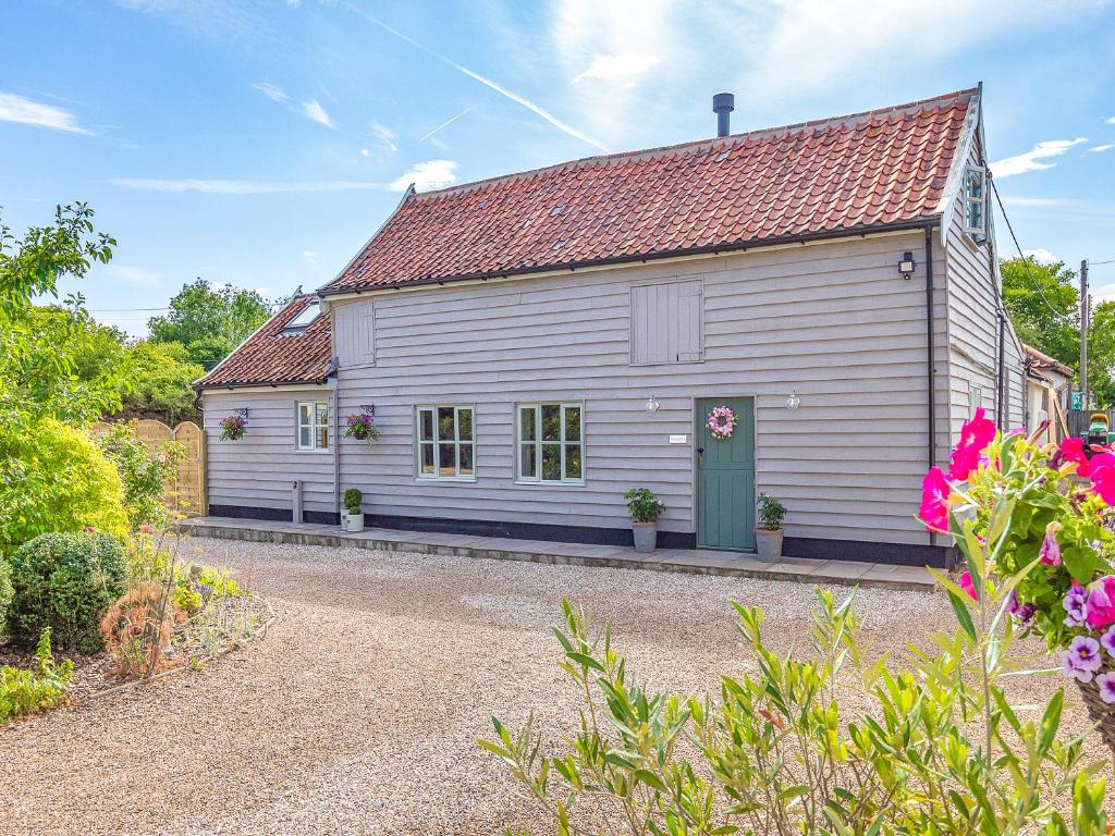 a white house with a green door and some flowers at Queens Barn in Wortham