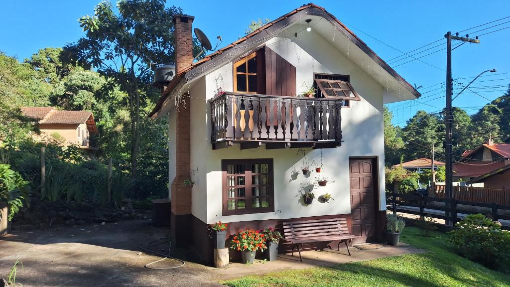 a white house with a balcony and a bench at Chalé Recanto Boreal in Monte Verde