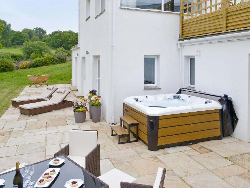a patio with a jacuzzi tub in a yard at Honey Pippin in Cheriton Bishop