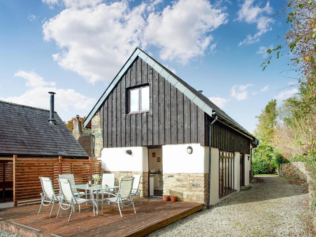 a barn conversion with a table and chairs on a deck at Uk45541-Old Stable Cottage in Sticklepath